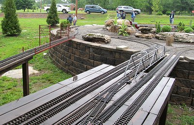 Ken Miller's railroad is extensive, but also in recovery after a tornado and two bad floods 'rearranged' it substantially within the last several months.  It uses retaining-wall-and-dirt, post, and raised platform construction.  This photo shows a bit of all three. Click for bigger photo.