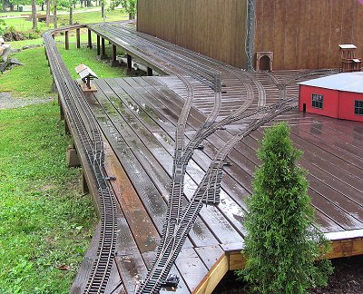 Ken Miller's railroad is extensive, but also in recovery after a tornado and two bad floods 'rearranged' it substantially within the last several months. This passing-track and switchyard section of the railroad uses post and raised-platform construction. Click for bigger photo.