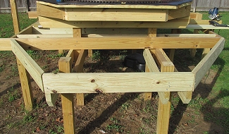 This picture shows how I added three 4'-long joists to extend the table length out past the posts (those are the pieces that are notched on the bottom). Then I toenailed in the end piece and cut the the two diagonal outside frame pieces. Click for bigger picture.
