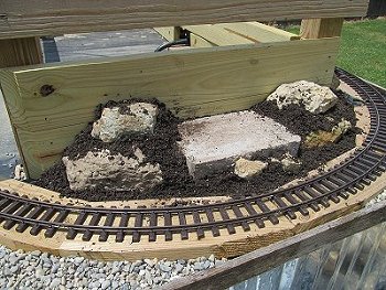 Layering rocks and dirt to created a sort of raised rock garden for a raised railroad.  Click for bigger photo.