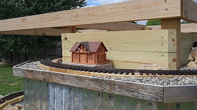 A toy log cabin sitting on a concrete block on the upper level.  Click for bigger photo.