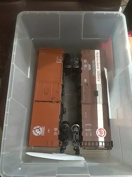 Two Aristocraft freight cars laying truck-to-truck in a 56qt Sterilite container.  Bachmann freight cars and coaches will fit just as well, as will Aristocraft 'woodie'coaches. A piece of corrugated cardboard goes on top of these, then two more cars.  I wouldn't ship these in the mail this way, but this is safe enough for getting from the garage to the railroad. Click for bigger photo.