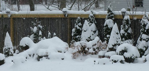 Part of our railroad during an early snowfall in 2010.  The lamps aren't shining, but you can tell how the lamps and the additional framing 