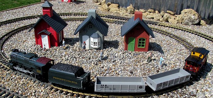 From our 'Garden Railroading on a ShoeString' article: three North States feeders buried up to the top of their feed trays in gravel, circled by an inexpensive battery-powered train.  Click for bigger photo.